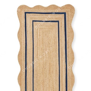 May include: A natural fiber rug with a scalloped edge and a double border of navy blue trim.