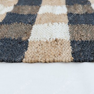 May include: A checkered rug with black, white, and brown squares. The rug is made of a woven material and has a textured surface.