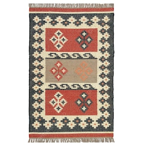 May include: A rectangular rug with a geometric pattern in shades of red, black, white, and beige. The rug has a fringe border.