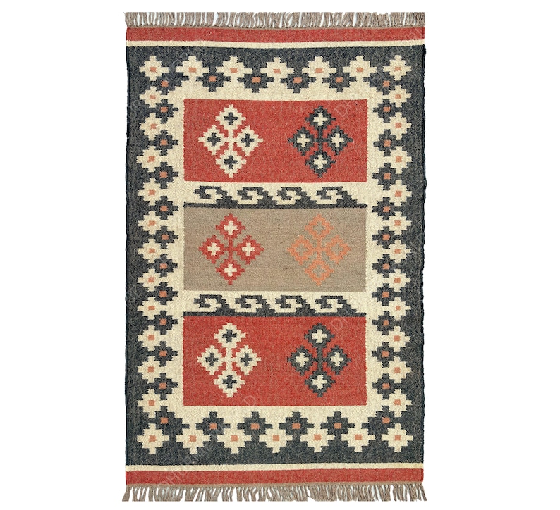 May include: A rectangular rug with a geometric pattern in shades of red, black, white, and beige. The rug has a fringe border.