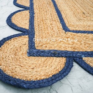 May include: A natural fiber rug with a blue border. The rug has a scalloped edge and is made of woven jute.