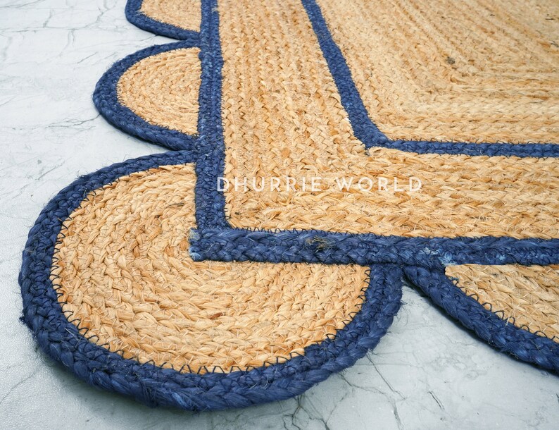 May include: A natural fiber rug with a blue border. The rug has a scalloped edge and is made of woven jute.