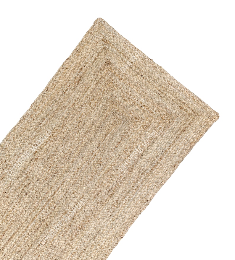 May include: A natural fiber rug made from jute, a sustainable and durable material. The rug has a woven texture and a light brown color. It is a rectangular rug with a fringed edge.