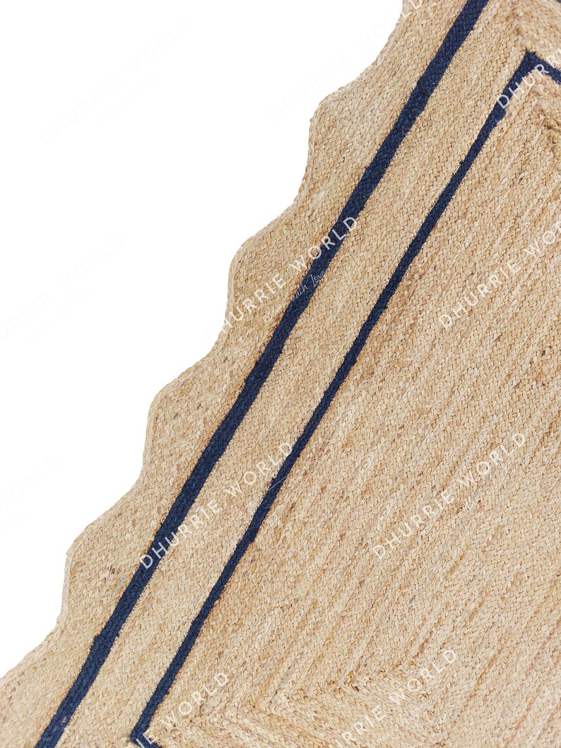 May include: A natural fiber rug with a wavy edge and two navy blue stripes. The rug is made of jute and has a natural, earthy color.