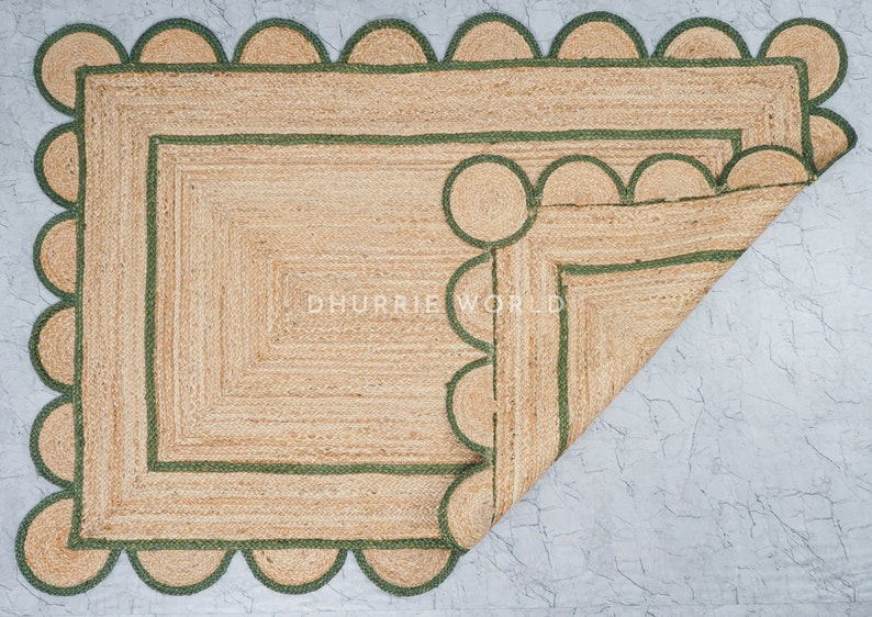 May include: A natural fiber rug with a green scalloped border. The rug is folded in half, revealing a second layer of green trim.