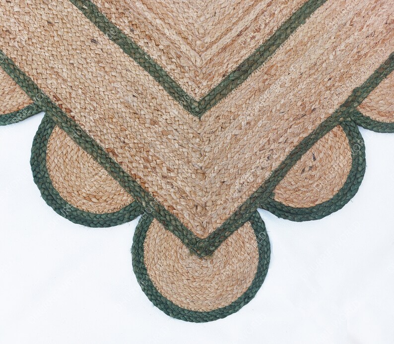 K&ouml;nnte beinhalten: Ein Jute-Teppich mit einem gewellten Rand und einem gr&uuml;nen Saum. Der Teppich ist aus Naturfasern gefertigt und hat einen rustikalen Look.