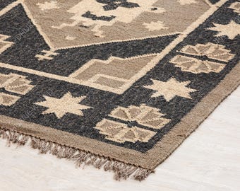 May include: A black and beige patterned rug with a fringe border. The rug has a geometric design with stars and other shapes.