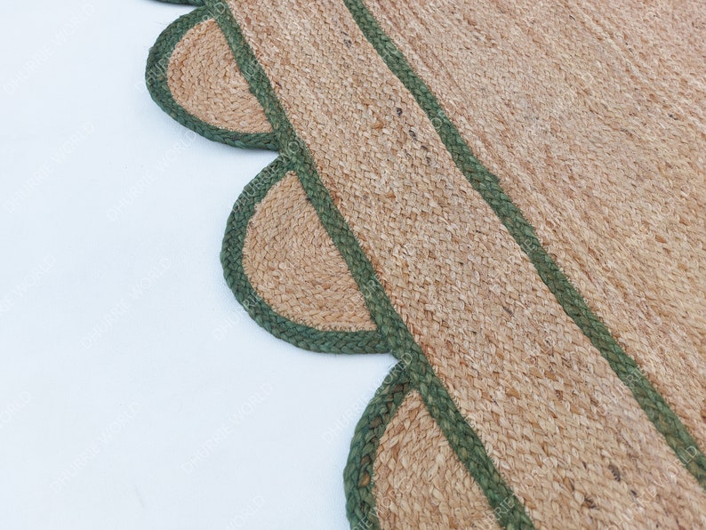 K&ouml;nnte beinhalten: Ein Naturfaser-Teppich mit einem gewellten Rand und gr&uuml;nem Besatz. Der Teppich ist aus Jute und hat eine nat&uuml;rliche, erdige Farbe.