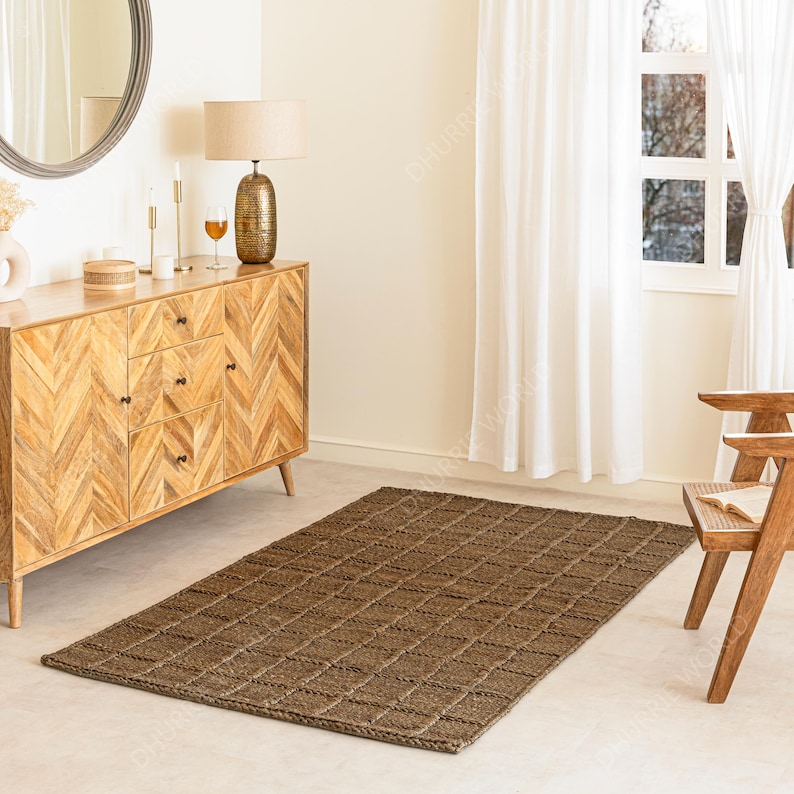 Puede incluir: Una alfombra rectangular de yute marr&oacute;n con un patr&oacute;n de diamantes se encuentra sobre un suelo claro. La alfombra est&aacute; en una habitaci&oacute;n con un aparador de madera, una l&aacute;mpara, un espejo y una silla de madera. La habitaci&oacute;n tiene cortinas blancas y una ventana.