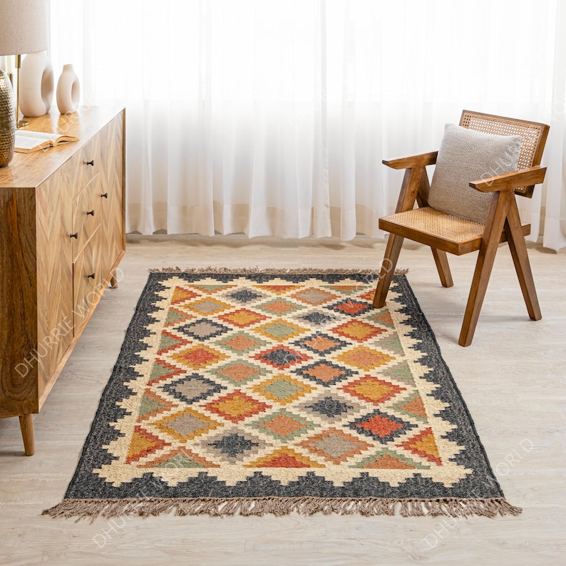 May include: A colorful, geometric patterned rug with a black background and fringe edges. The rug is made of jute and wool and has a hand-woven look.