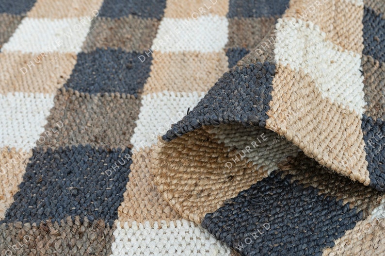 May include: A checkered rug made of natural fibers in shades of brown, beige, and white. The rug is woven in a checkered pattern with a textured surface.