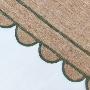 K&ouml;nnte beinhalten: Nahaufnahme eines Naturfaser-Teppichs mit einem gewellten Rand. Der Teppich hat einen gr&uuml;nen Rand und ist aus einem gewebten Material.