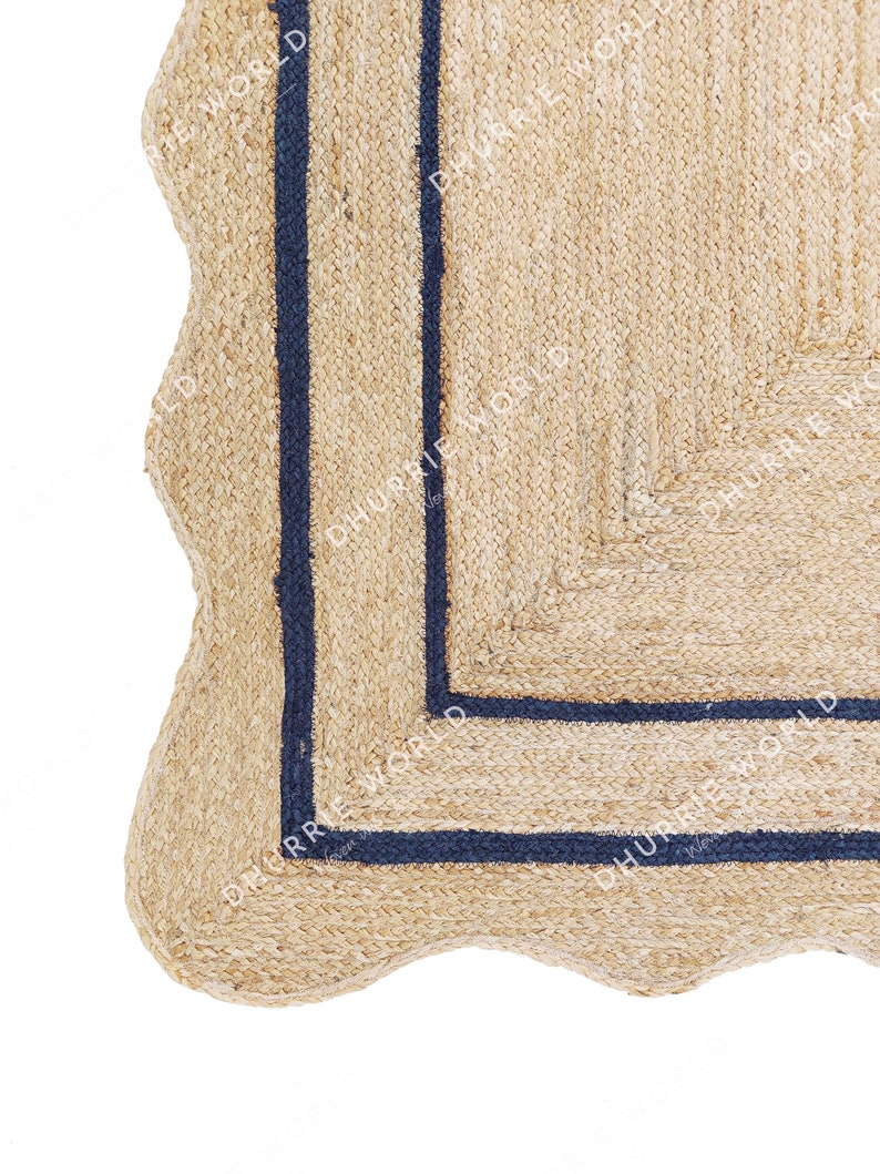 May include: A close-up of a natural fiber rug with a wavy edge and a dark blue border. The rug is made of jute and has a natural, earthy look.