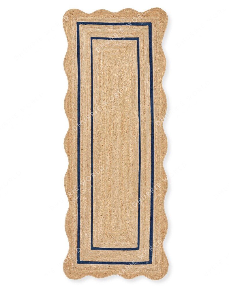 May include: A long, rectangular jute rug with a scalloped edge and a double navy blue border. The rug is made of natural fibers and has a rustic, farmhouse style.
