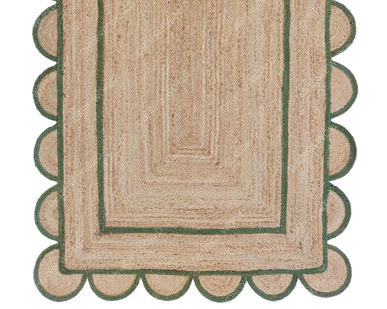 K&ouml;nnte beinhalten: Ein Naturfaser-Teppich mit gr&uuml;nem Rand und gewellten Kanten. Der Teppich hat eine gewebte Textur und eine neutrale Farbe.