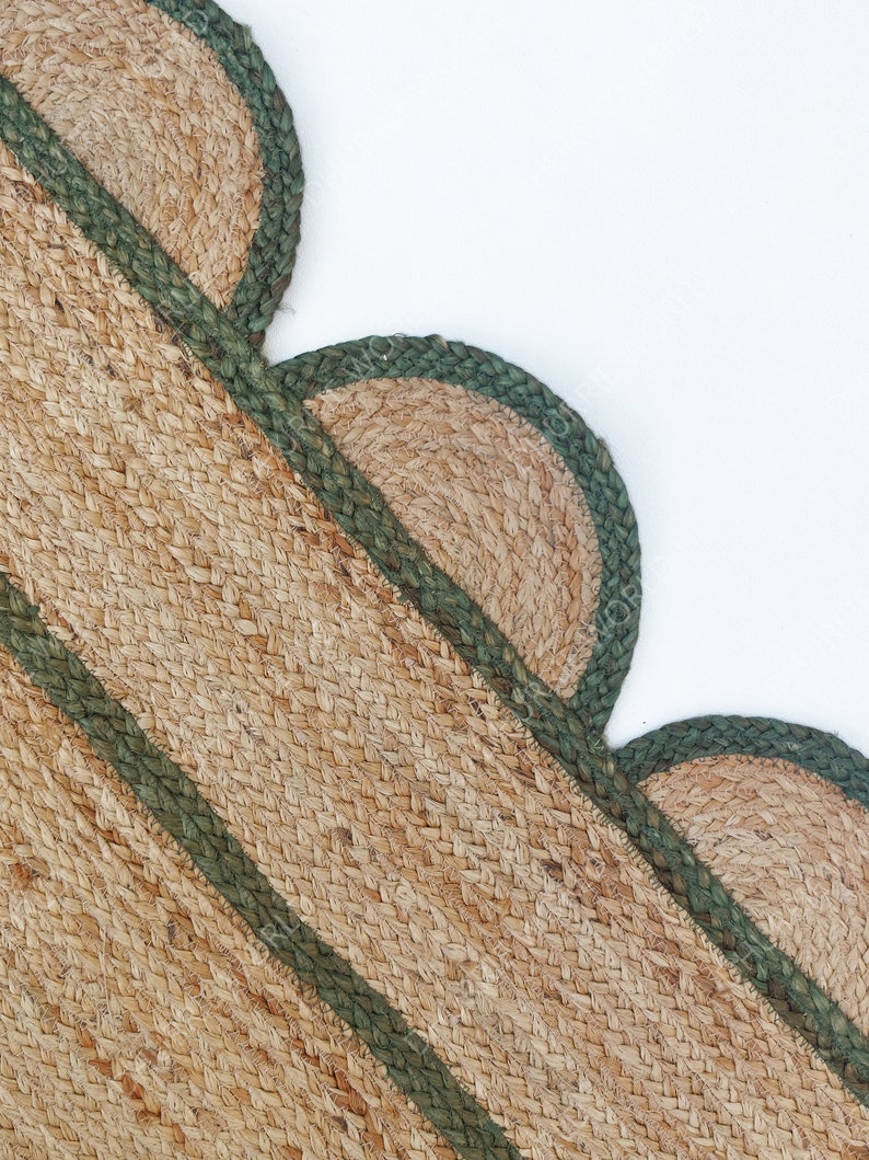 K&ouml;nnte beinhalten: Ein Naturfaser-Teppich mit gr&uuml;nem Rand. Der Teppich hat einen gewellten Rand und ist diagonal gewebt.