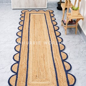 May include: A natural fiber rug with a scalloped edge and a navy blue border. The rug is made of jute and is perfect for adding a touch of natural beauty to any room.