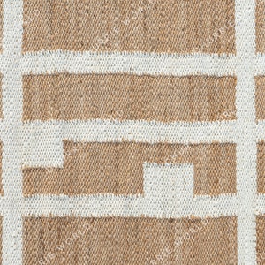 May include: A close-up of a woven rug with a geometric pattern. The rug is made of natural fibers and has a light brown color with white lines forming a grid pattern.