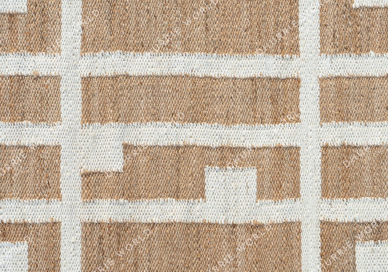 May include: A close-up of a woven rug with a geometric pattern. The rug is made of natural fibers and has a light brown color with white lines forming a grid pattern.