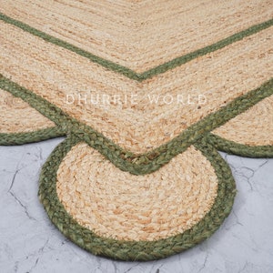 May include: A natural fiber rug with a scalloped edge and a green border. The rug is made of jute and has a natural, earthy look.