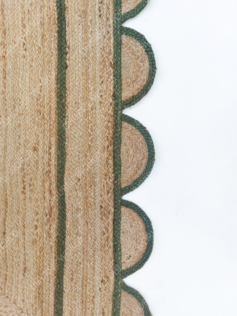 K&ouml;nnte beinhalten: Ein Naturfaser-Teppich mit gr&uuml;nem Rand und einem gewellten Saum. Der Teppich ist aus Jute und hat eine nat&uuml;rliche, erdige Farbe.