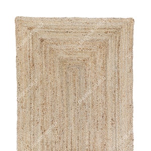 May include: A natural fiber rug with a woven design. The rug is made of jute and has a light brown color.