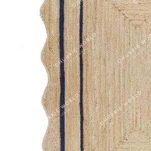 May include: A natural fiber rug with a woven texture and two dark blue stripes running vertically down the center. The rug has a scalloped edge.
