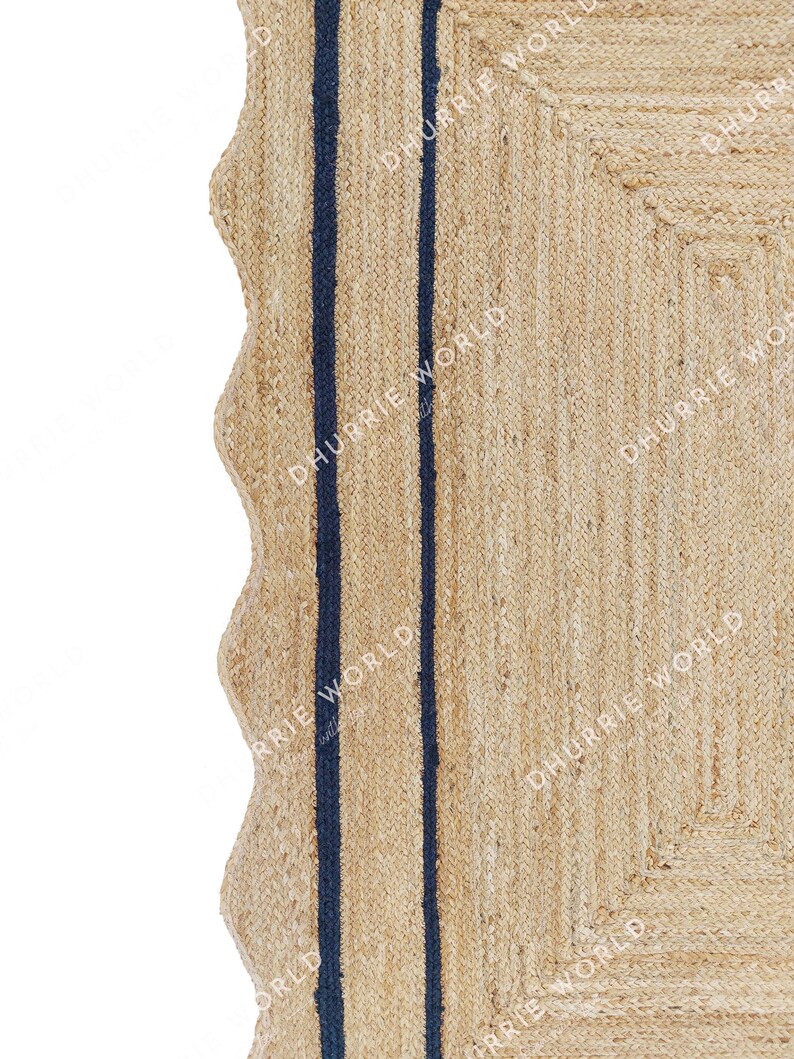 May include: A natural fiber rug with a woven texture and two dark blue stripes running vertically down the center. The rug has a scalloped edge.