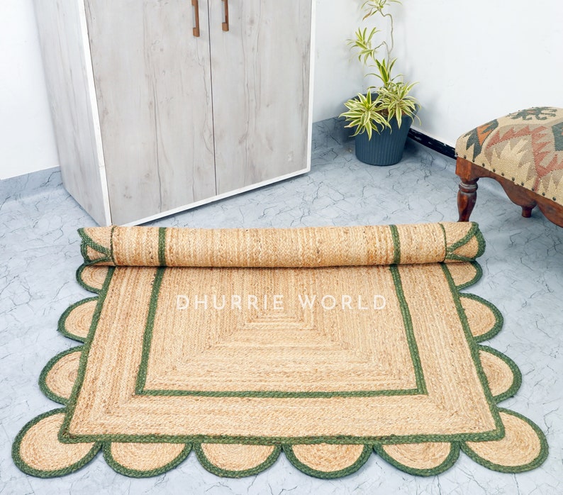 May include: A natural fiber rug with a green border and scalloped edges. The rug is rolled up and the text "DHURRIE WORLD" is visible in the center.