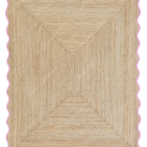 Puede incluir: Una alfombra de fibra natural con un patr&oacute;n geom&eacute;trico de color marr&oacute;n claro. La alfombra tiene un borde rosa festoneado.