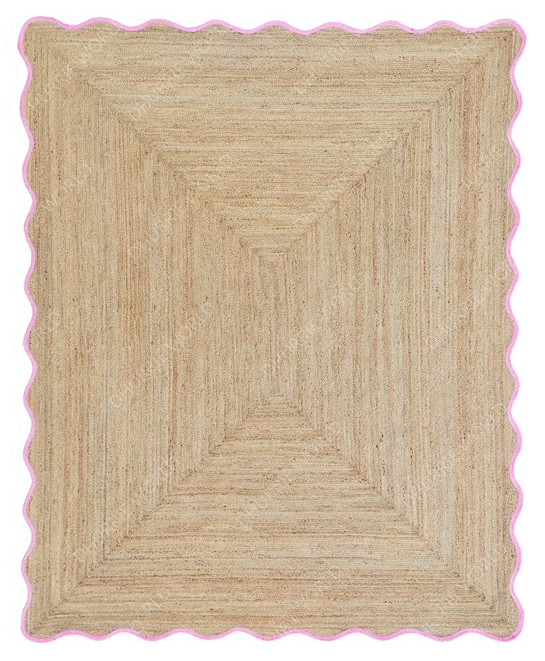 Puede incluir: Una alfombra de fibra natural con un patr&oacute;n geom&eacute;trico de color marr&oacute;n claro. La alfombra tiene un borde rosa festoneado.