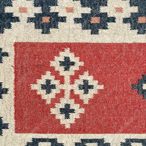 May include: A close-up of a red and white woven rug with a geometric pattern. The rug has a dark blue border and a central design of four white squares with black crosses.