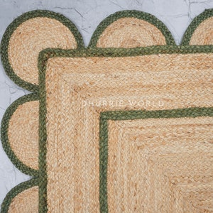 May include: A square jute rug with a green border. The rug has a scalloped edge with a green border. The rug is made of natural fibers and has a rustic look.