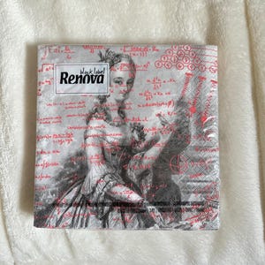 May include: A square package of Renova black label napkins. The napkins feature a black and white image of a woman in a historical dress, overlaid with red mathematical equations. The Renova logo is in a white rectangle.