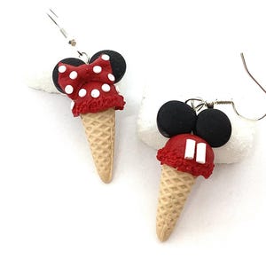 Peut inclure: Une paire de boucles d'oreilles pendantes en forme de cornets de glace rouge et blanc avec des oreilles de Mickey Mouse noires sur le dessus. Les boucles d'oreilles sont en pâte polymère et ont des crochets argentés.