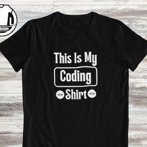 Op de afbeelding: Zwart T-shirt met witte tekst die "This is my Coding Shirt" luidt met haakjes om het woord "Shirt".
