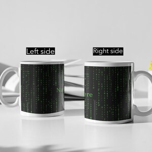 Może przedstawiać: Dwa białe ceramiczne kubki z czarno-zielonymi wzorami kodu macierzowego. Lewy kubek ma nadrukowane słowo "Name". Prawy kubek ma nadrukowane słowo "Here".