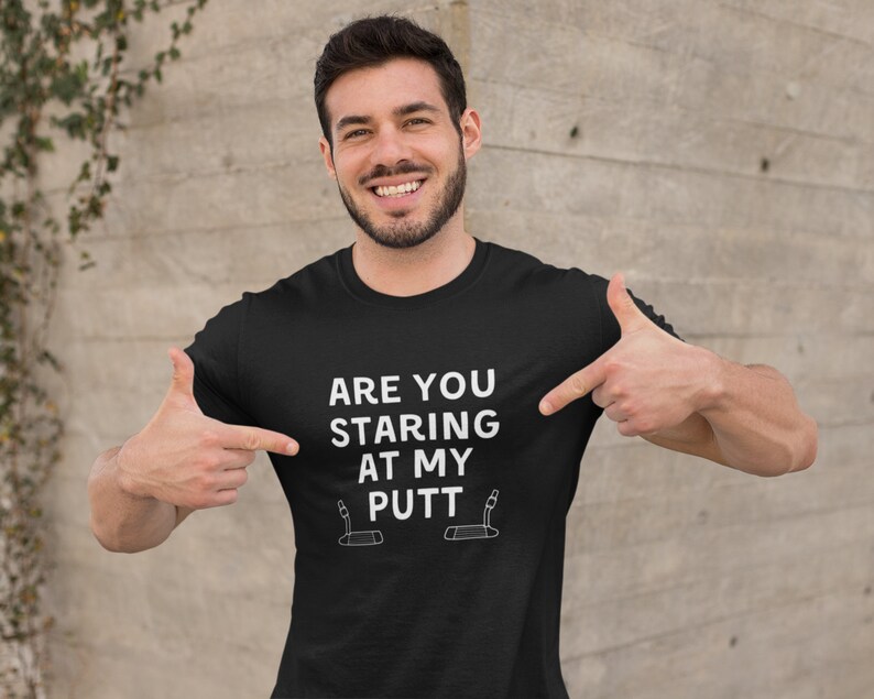 May include: A black t-shirt with white text that reads "Are you staring at my putt?" and a graphic of a golf putter.