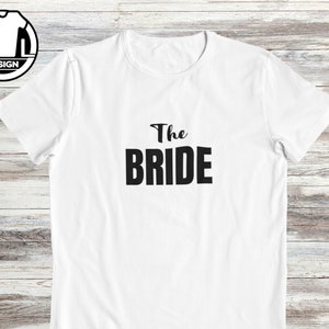 Pode incluir: Camiseta branca com texto preto que diz "The Bride".