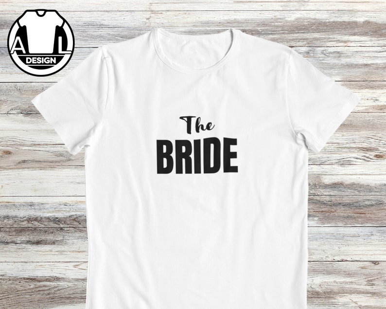 Pode incluir: Camiseta branca com texto preto que diz "The Bride".