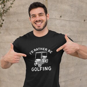 May include: Black t-shirt with white text that reads "I'd rather be golfing" and a white illustration of a golf cart.