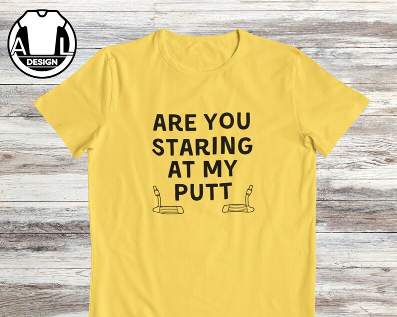 May include: Yellow t-shirt with black text that reads "Are you staring at my putt" with a golf putter graphic below the text.