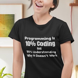 Op de afbeelding: Een zwart t-shirt met korte mouwen en witte tekst: Programming Is 10% Coding And 90% Understanding Why It Doesn't Work. Het shirt heeft een ronde hals en een standaard pasvorm, waarbij de bedrukte tekst duidelijk op de borst is weergegeven.