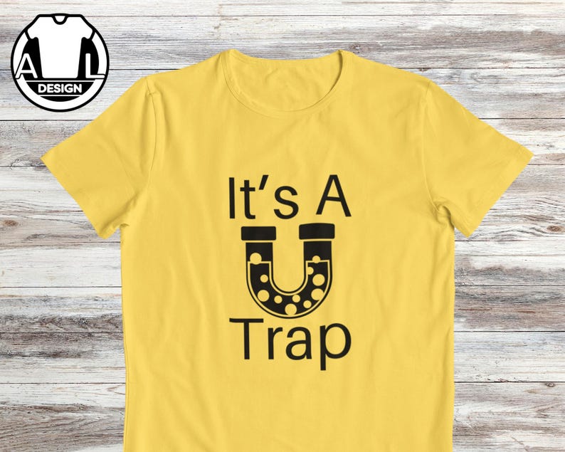 May include: Yellow t-shirt with black text that reads "It's A U Trap" with a black horseshoe-shaped graphic with white dots inside.