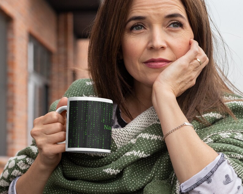 Może przedstawiać: Biały kubek ceramiczny z czarno-zielonym wzorem przedstawiającym kod w stylu macierzy i słowo "NaN".