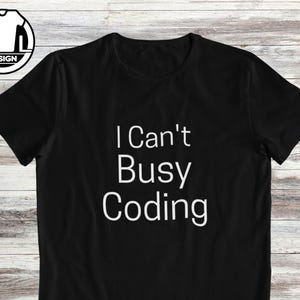 May include: Black t-shirt with the white text "I Can't Busy Coding". The top has a crew neck and short sleeves. A white and black logo is in the upper left corner.