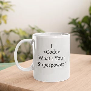 Peut inclure: Une tasse en céramique blanche avec du texte noir qui dit "I <Code> What's Your Superpower?"