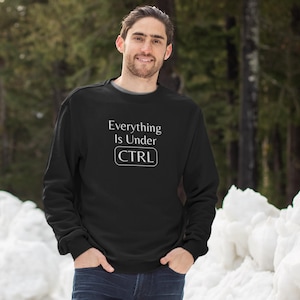 Könnte beinhalten: Schwarzer Pullover mit dem Text "Everything is Under CTRL" in Weiß.