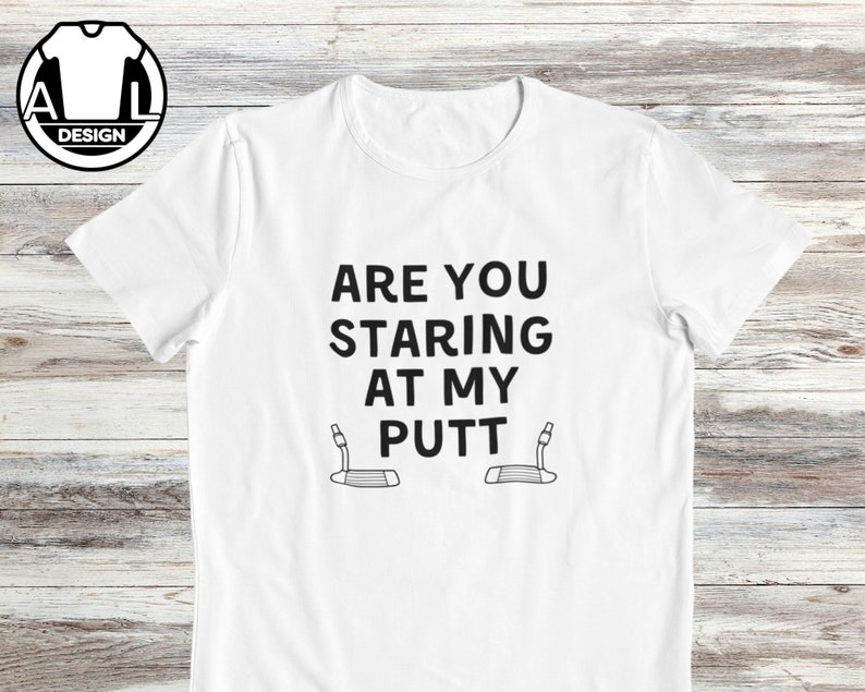 May include: White t-shirt with black text that reads "Are you staring at my putt?" with a golf putter graphic on each side of the text.