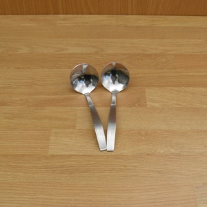 May include: Two silver serving spoons with a polished finish and a slightly curved handle.